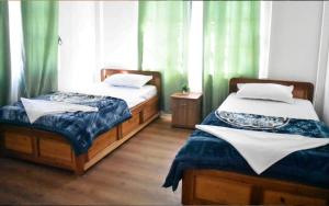 two beds in a room with green curtains at khim Retreat in Mirik