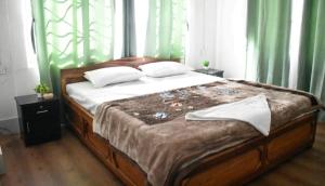 a bedroom with a large bed with green curtains at khim Retreat in Mirik