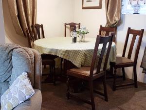a dining room table with chairs and a table with flowers on it at Hendy in Llanfaelrhys