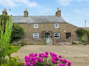 a stone house with purple flowers in front of it at Hendy in Llanfaelrhys