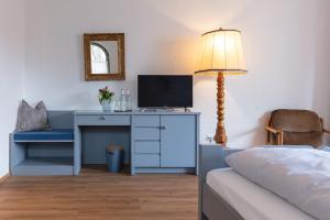 a bedroom with a desk with a computer and a lamp at Hotel Bihler in Bad Aibling