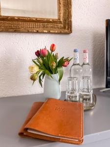 a table with a book and a vase of flowers and bottles at Hotel Bihler in Bad Aibling