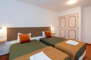 a bedroom with two beds with green and orange pillows at Quinta da Torre in Torre