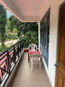 a balcony with a table and chairs and a door at Darap Dzimkha in Pelling