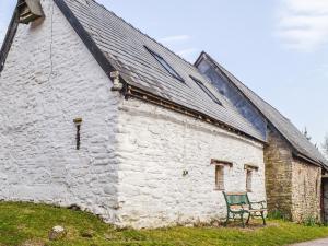 a green bench sitting outside of a white building at Ty Fferm Hen - Uk36420 in Talybont +6 photos