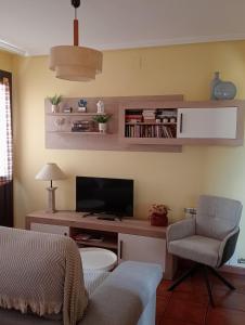 a living room with a tv and a couch and a chair at Apartamentos El Brezo in Albarracín