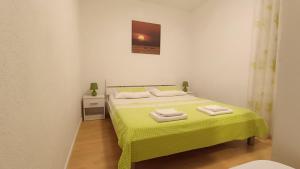 a bedroom with a green bed with a yellow blanket at Wind Rose Apartments Sumartin in Sumartin
