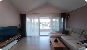 a living room with a couch and a flat screen tv at Wind Rose Apartments Sumartin in Sumartin