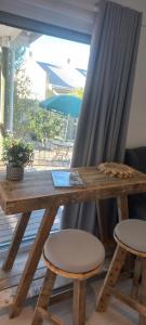a wooden table and two stools in front of a window at 2 on Fifth Avenue in Botrivier +12 photos