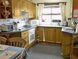 a kitchen with wooden cabinets and white appliances at Swallow's Nest - E3245 in Crackenthorpe +3 photos