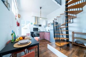 a kitchen with a table and a spiral staircase at Casa do Vento in Aljezur