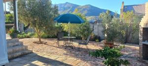a patio with a table and chairs and an umbrella at 2 on Fifth Avenue in Botrivier
