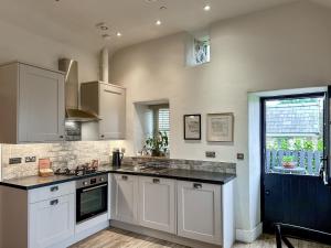 a kitchen with white cabinets and a black counter top at Blakeskerra Barn in Kenfig