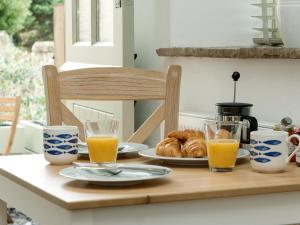 a table with a breakfast of orange juice and croissants at Blakeskerra Barn in Kenfig