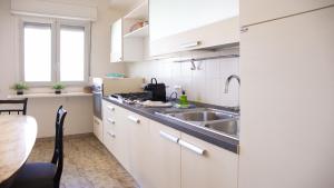 a kitchen with white cabinets and a sink and a table at Solemar Sicilia - Casa Bella in Bagheria
