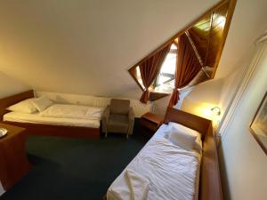 a small room with two beds and a chair at Hotel Főnix in Pécs