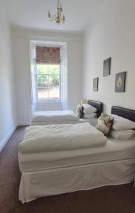 two beds in a white room with a window at Garden Flat- Private Luxury in Ashkirk