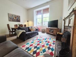 a living room with a couch and a tv at Garden Flat- Private Luxury in Ashkirk