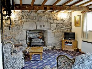 a stone walled living room with a stone fireplace at Cruck End - E3749 in Crackenthorpe