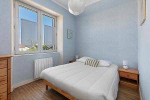 a bedroom with a large white bed and a window at Villa Timao Plage in Batz-sur-Mer