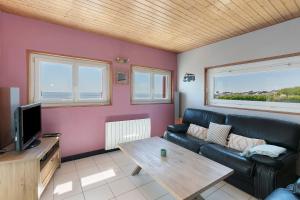 a living room with a black leather couch and a table at Villa Timao Plage in Batz-sur-Mer