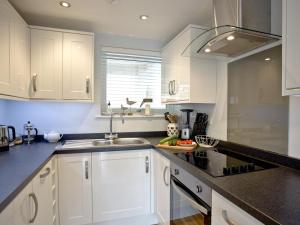 a kitchen with white cabinets and a sink at Dunlin 1 - The Cove in Brixham +6 photos