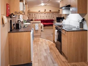 a kitchen with wooden cabinets and a living room at Glen Y Nant in Llanfihangel-nant-Melan