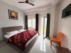 a bedroom with a bed and a chair and a window at Hotel Ganpati place in Uttarkāshi