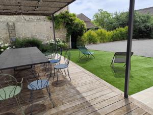 a wooden deck with chairs and a table and a lawn at Les Griottes Gite de charme in Verdigny