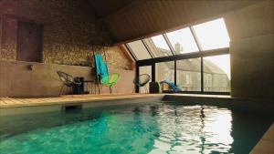 a swimming pool with chairs and a large window at Les Griottes Gite de charme in Verdigny