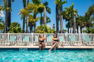 two women in bathing suits sitting on the edge of a swimming pool at Sugarloaf Key RV Resort & Cottages in Summerland Key