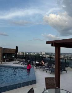 a person sitting next to a swimming pool on a building at Flat Innerbloom Manaus in Manaus