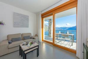 a living room with a couch and a large window at Residence degli Oleandri 2A in Argegno