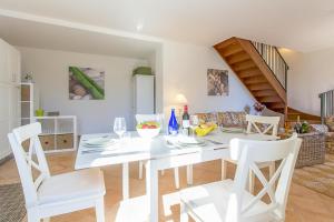 a white dining room with a white table and chairs at Casa Al Prato Apt. F in Varenna