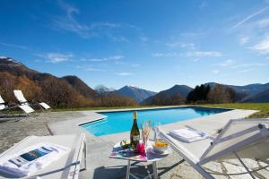 a table with a bottle of wine next to a swimming pool at Villa La Betulla in Cerano d'Intelvi