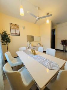 a dining room with a white table and white chairs at QD Apartment Simba Unit in Arusha
