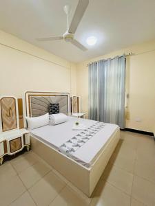 a bedroom with a large bed with a ceiling fan at QD Apartment Simba Unit in Arusha