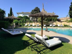 two lounge chairs and umbrellas next to a swimming pool at Villa Jerez in Jerez de la Frontera