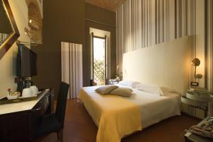 a bedroom with a bed with a desk and a television at Hotel De La Pace, Sure Hotel Collection by Best Western in Florence +82 photos