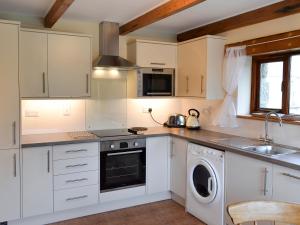 a kitchen with white cabinets and a washer and dryer at The Paddock in Saint Hilary