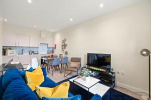 a living room with a blue couch and a kitchen at Hybrid Resi - London, Sutton, FREE on-site Car or Van parking in Cheam