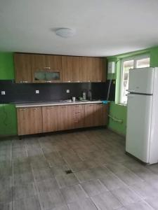 a kitchen with a white refrigerator and wooden cabinets at GuestHous LUKA in Manglisi
