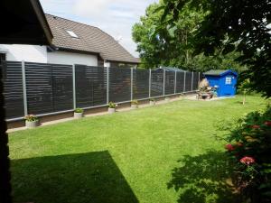 a fence in a yard with a grass yard at Haus Ferienglueck _ Lueth in Friedrichskoog +16 photos