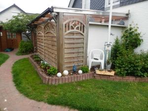 a garden with a pergola and a chair in a yard at Haus Ferienglueck _ Lueth in Friedrichskoog