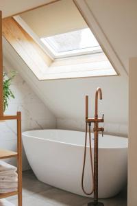 a bath tub in a bathroom with a skylight at Op Oost Boutique hotel & Restaurant het Kook Atelier in Oosterend +155 photos