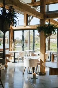 a restaurant with tables and chairs and large windows at Op Oost Boutique hotel & Restaurant het Kook Atelier in Oosterend