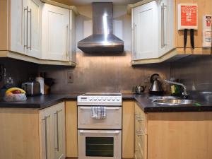 a kitchen with white cabinets and a stove and a sink at Valley View in Burnsall