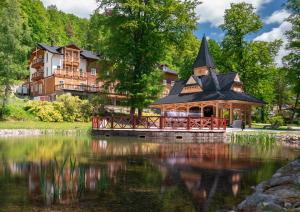 a house on the water in front of a lake at Hotel Maria & Spa Pieniny in Szczawnica