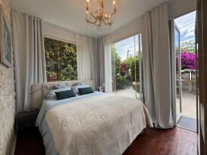 a bedroom with a bed with a chandelier and large windows at 7 Bdr Villa with Heated Pool & Spa in Mazotos +82 photos