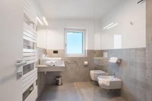 a bathroom with a sink and a toilet and a window at Bike Apartments Curti - Waldgrün in Laives +29 photos